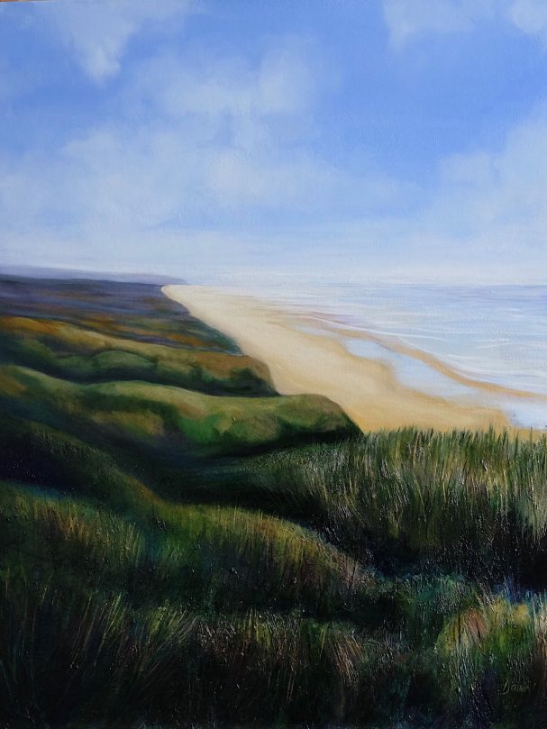 Coastal scene with sandy beach, low grass, and blue sky reflecting over calm water.